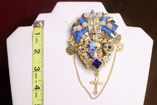 A large gold and blue brooch with a cross on it.