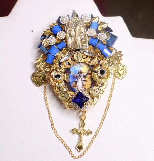 A gold and blue brooch with a cross on it.