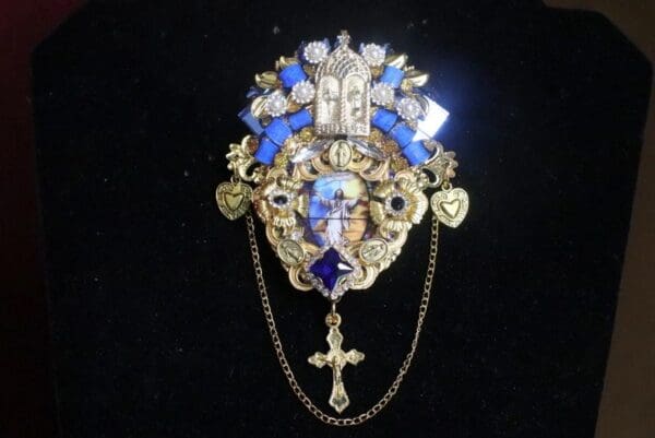 A gold and blue brooch with cross on it