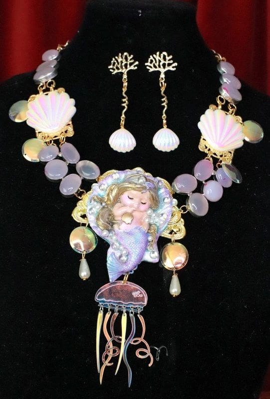 A necklace and earrings set with shells, pearls and a mermaid.