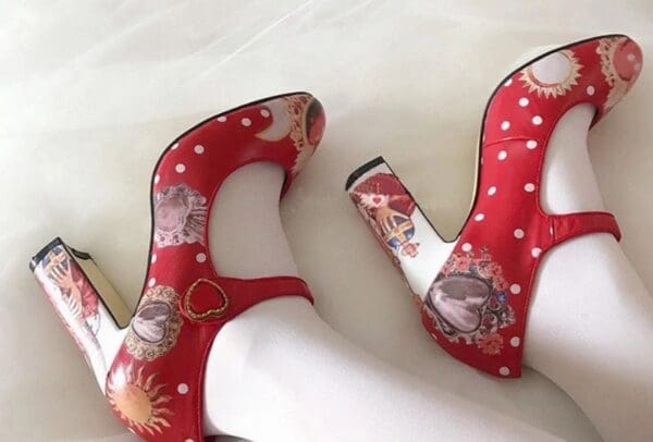 A pair of red shoes with white polka dots and cats.