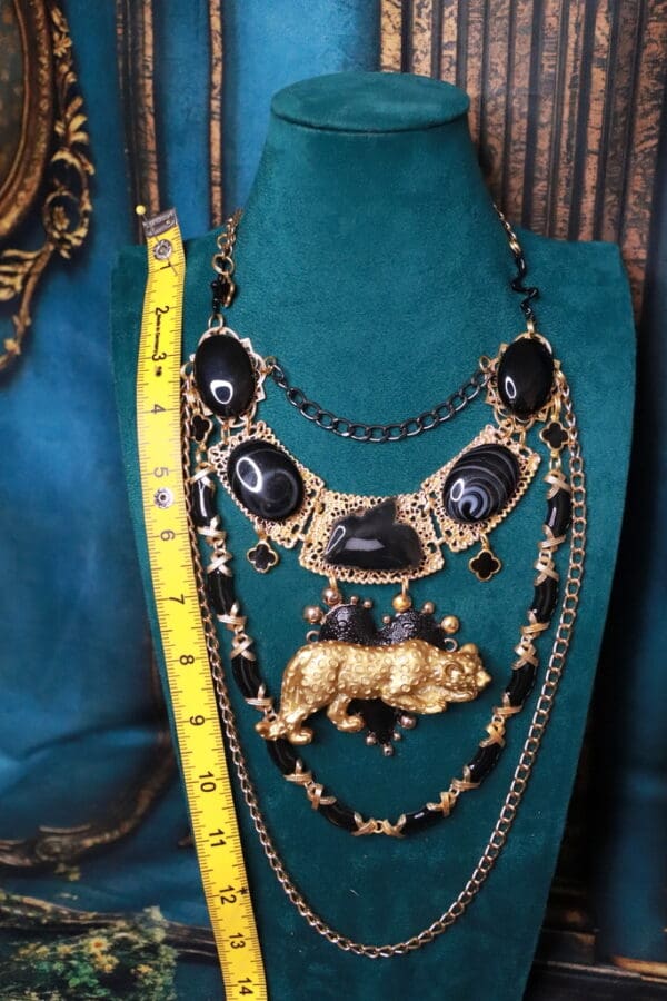 A necklace with a large black stone and gold animal.