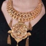 A woman wearing a gold chain necklace with tassels.