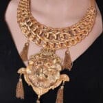 A woman wearing a gold chain necklace with tassels.