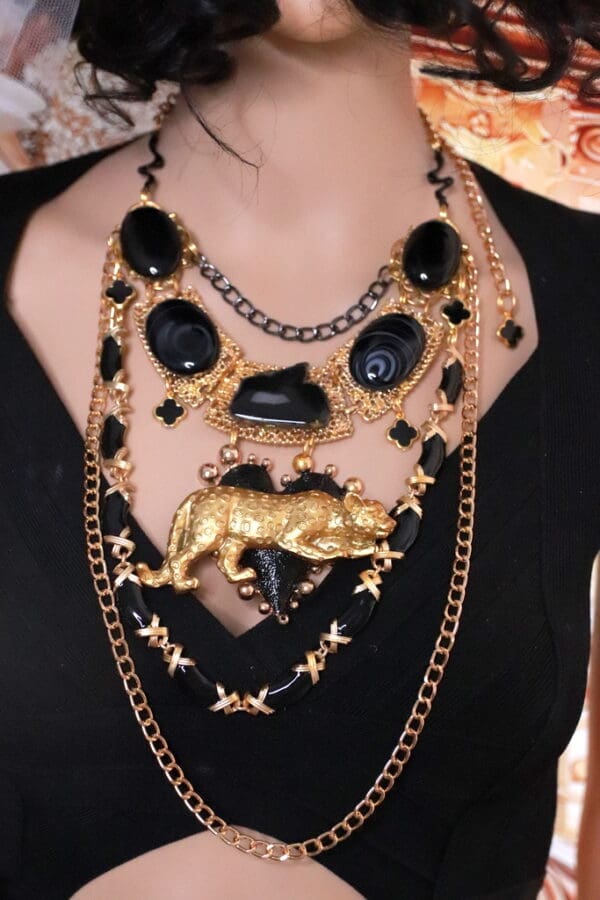 A woman wearing multiple necklaces with black and gold chains.