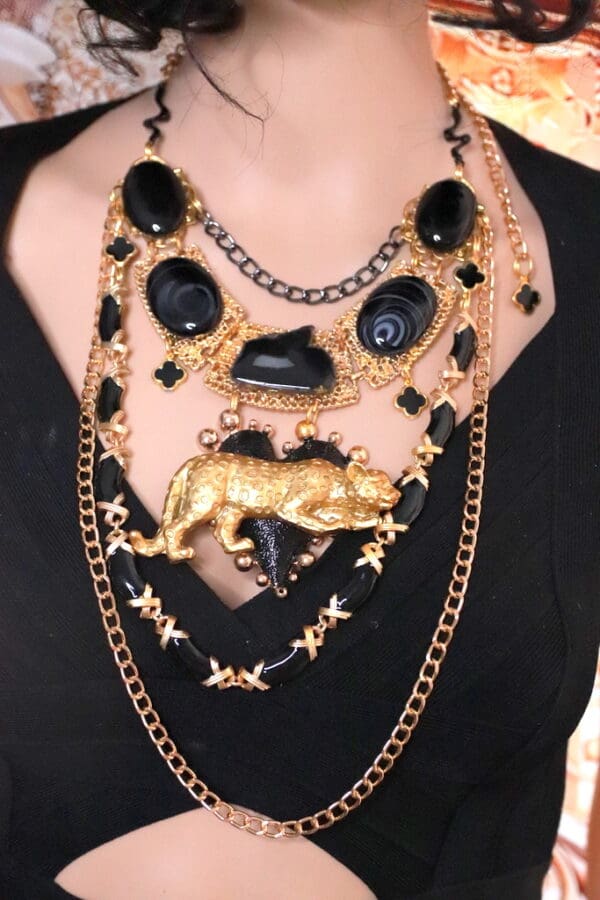 A woman wearing multiple necklaces with black and gold chains.