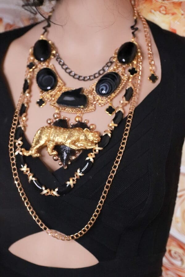 A woman wearing multiple necklaces with black and gold chains.