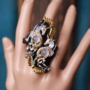 A hand wearing a ring with gold and silver flowers.