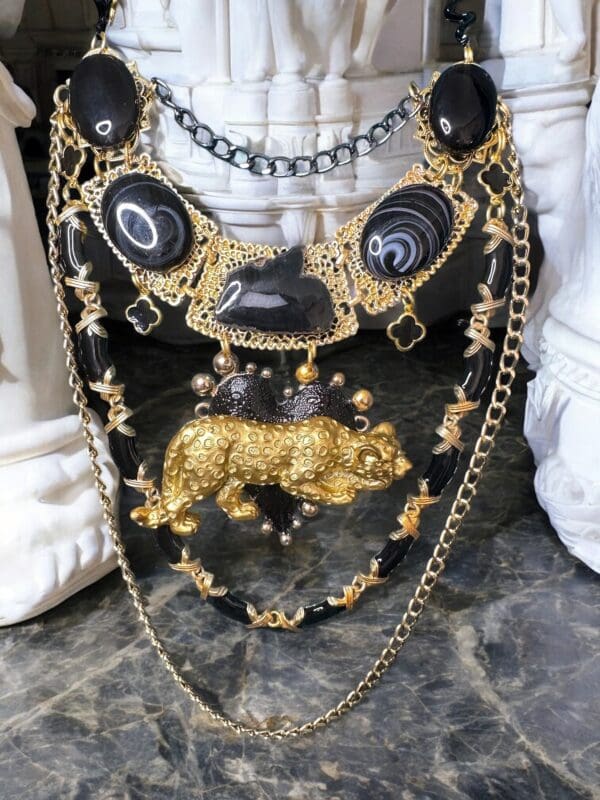 A black and gold necklace with an animal on it.