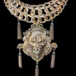 A chain link necklace with a lion head and tassels.