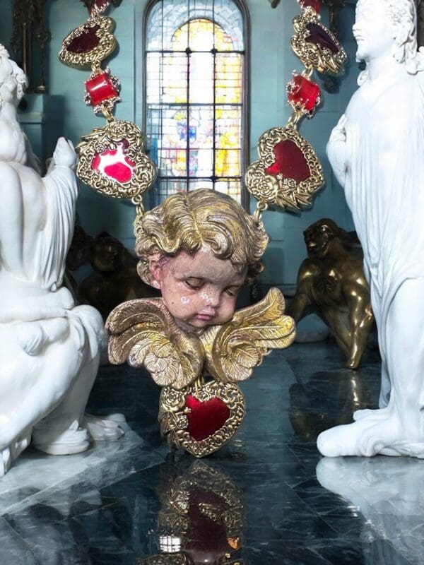 A statue of an angel with red hearts around it.