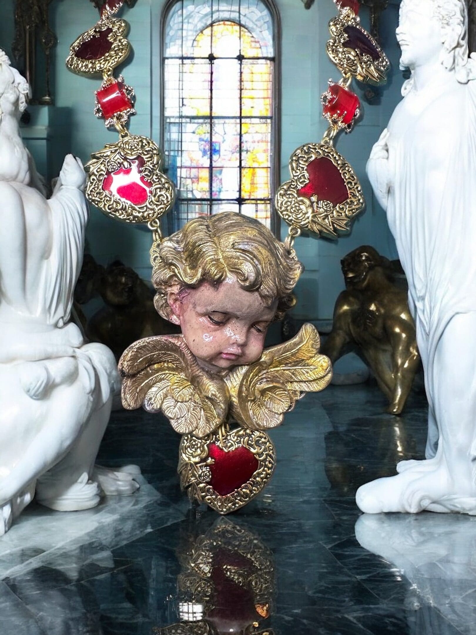 A statue of an angel with red hearts around it.