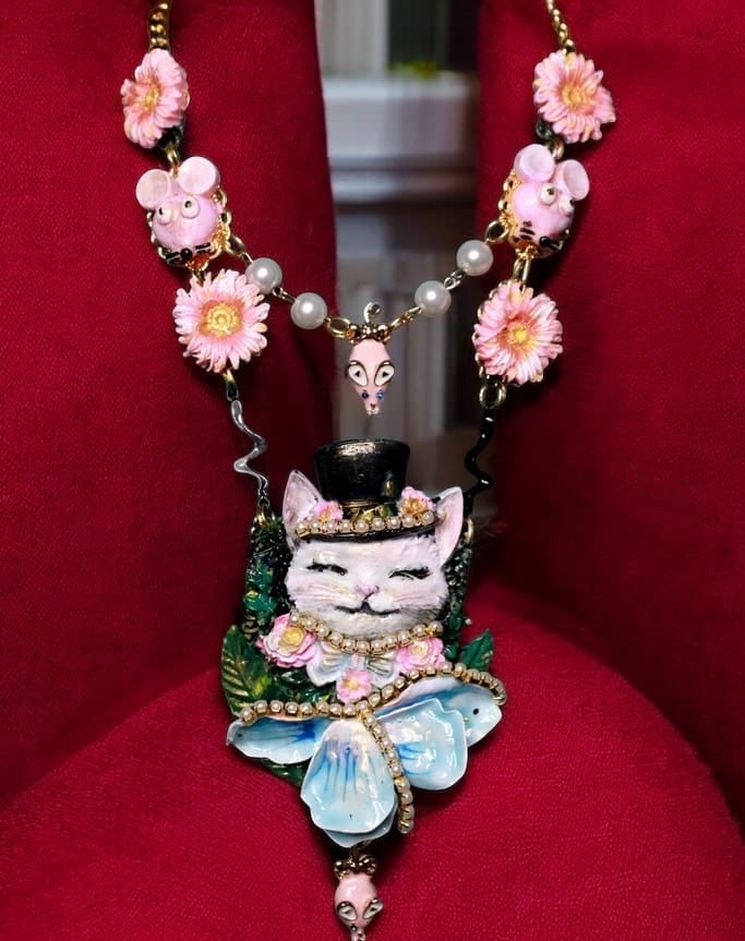 A necklace with a cat on it sitting in a chair.