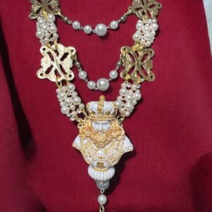 A necklace with a crown and pearls on it.
