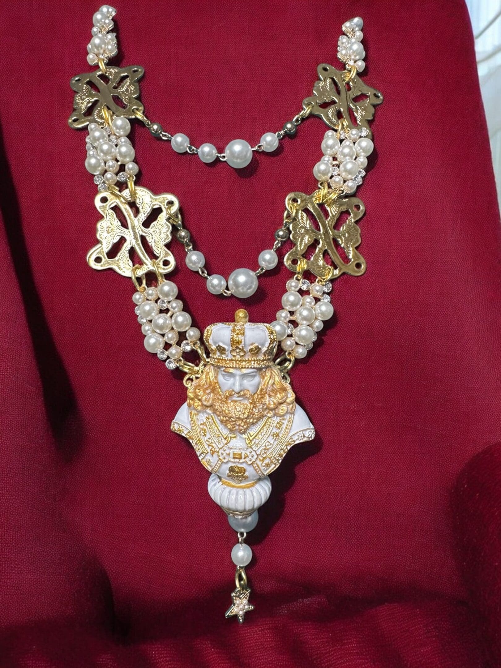 A necklace with a crown and pearls on it.