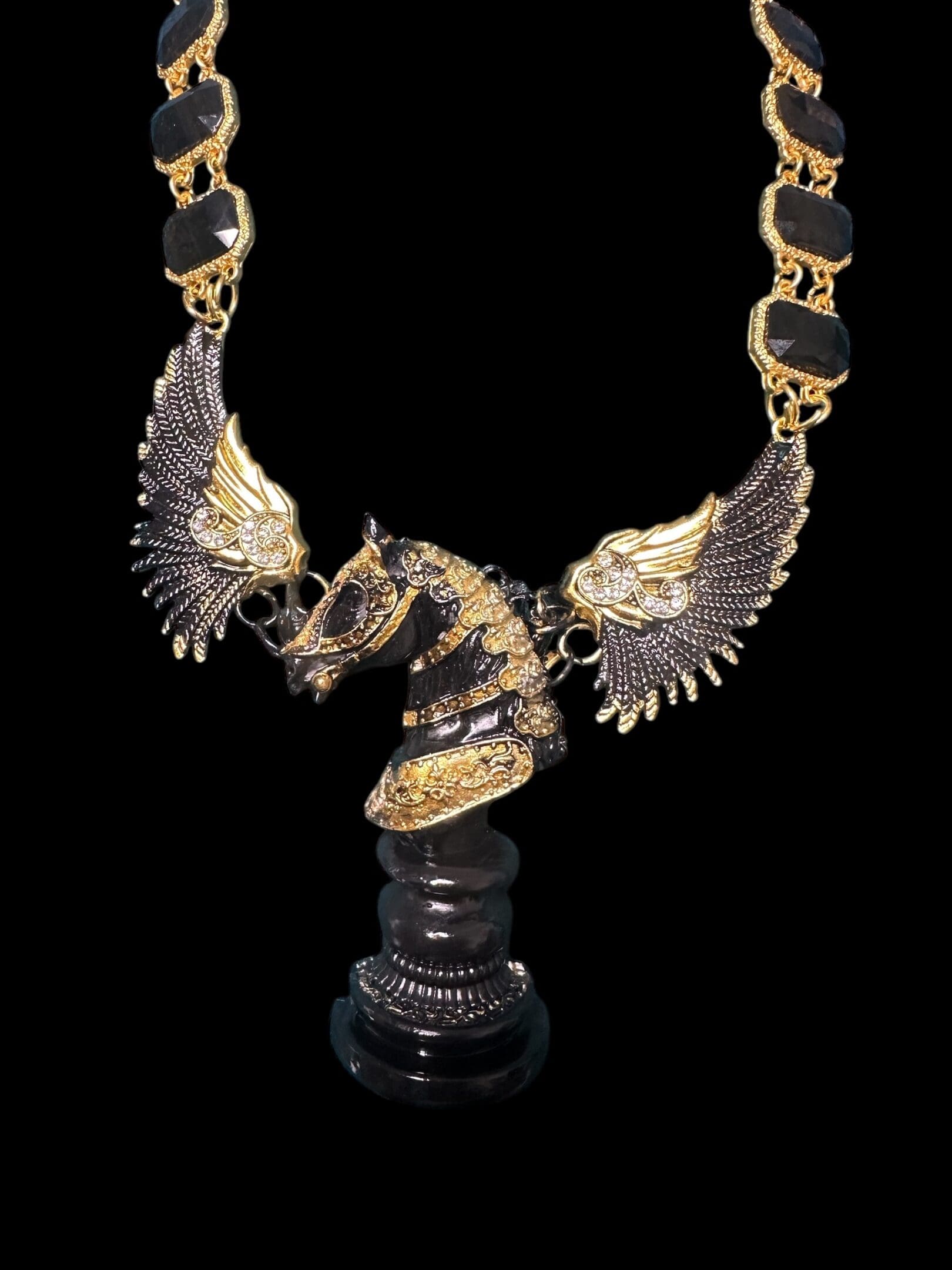 A black and gold necklace with a horse statue.