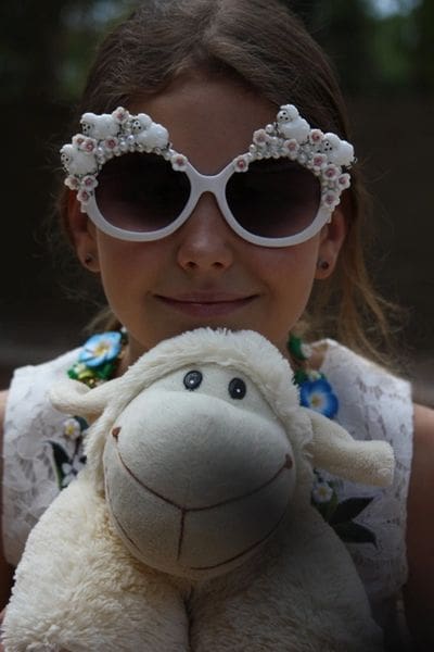 A girl in sunglasses holding a stuffed animal.