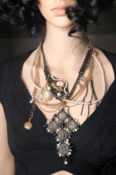 A woman wearing many different necklaces and chains.