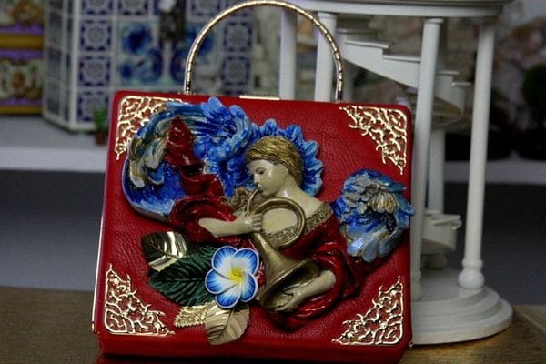 A red purse with a picture of an angel on it.