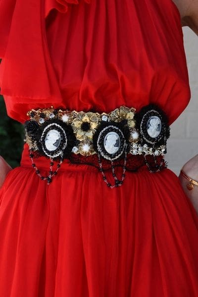 A woman wearing a red dress with three black and white cameo 's on it.