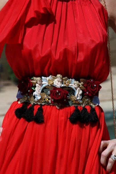 A woman wearing a red dress with tassels and flowers.