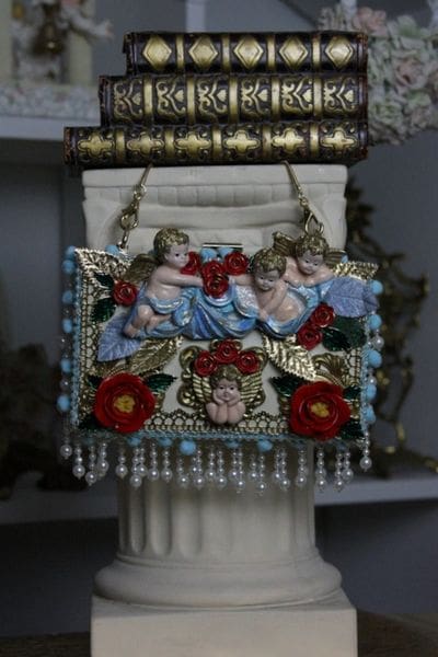 A decorative hanging ornament with angels and flowers.