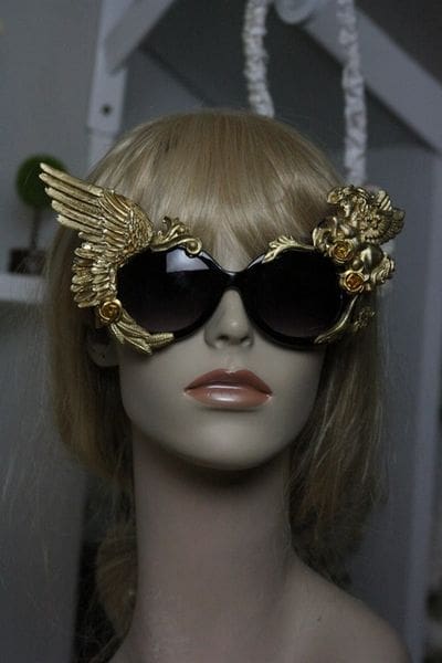 A mannequin wearing sunglasses with gold wings and a dragon head.