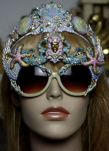 A mannequin wearing sunglasses with a crown on top of it.