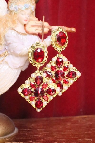 A pair of red earrings hanging from a gold chain.