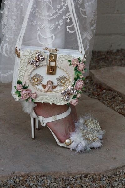 A white purse and high heel shoe on the ground.