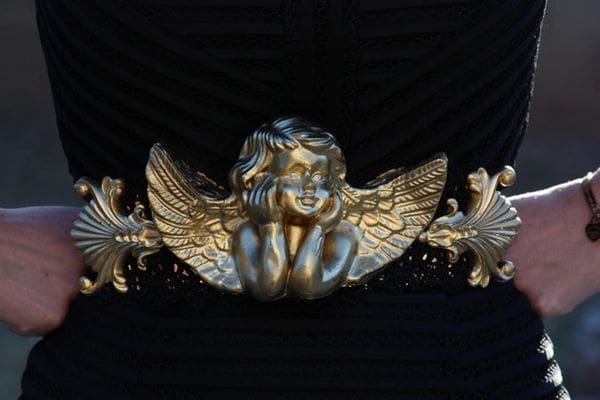 A gold statue of an angel sitting on top of a black surface.
