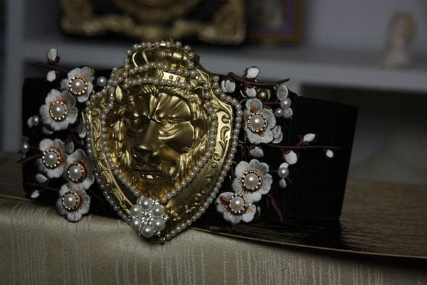 A gold and diamond lion head with flowers on top of it.