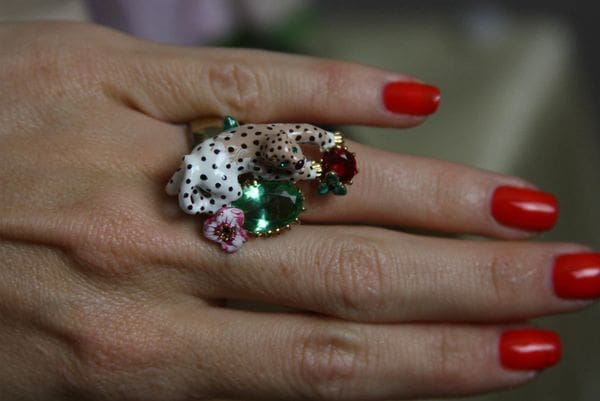 A woman 's hand with red nails and a ring on her finger.