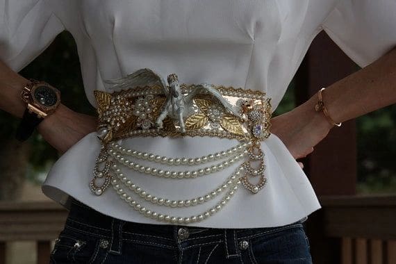 A woman wearing a white shirt and jeans with pearls.