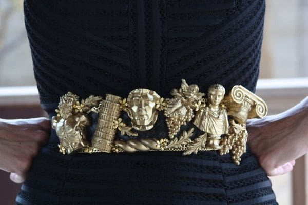 A woman wearing a black dress with gold jewelry.