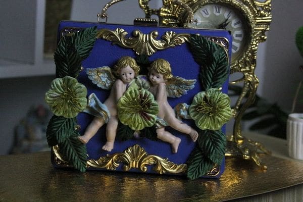 A blue purse with two angels on it.