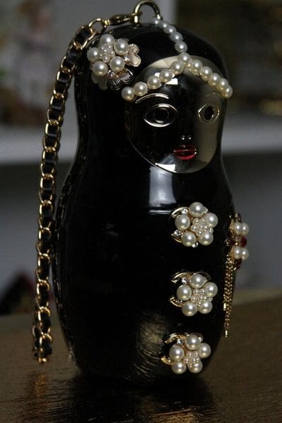A black russian doll with pearls and gold chain.
