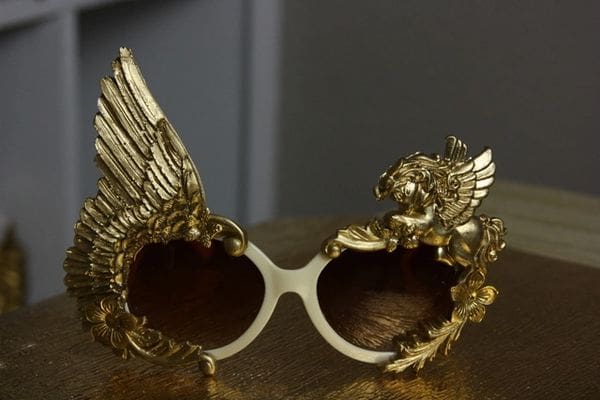A pair of gold sunglasses with wings on top.