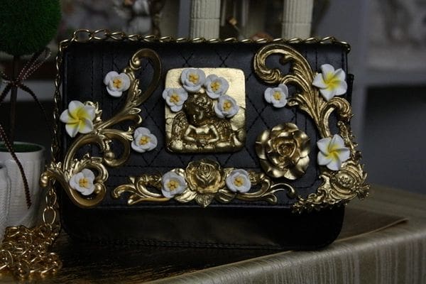 A black and gold purse with flowers on it.