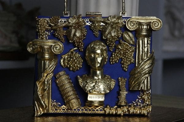 A gold statue of a woman with grapes and other decorations.