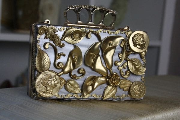 A silver and gold purse with some flowers on it