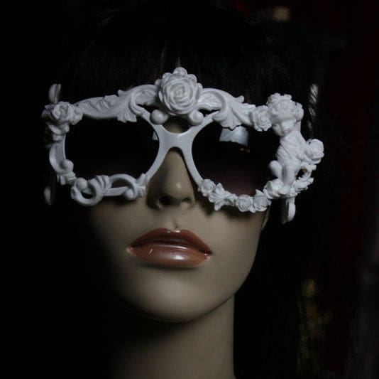 A mannequin wearing white sunglasses with ornate design.
