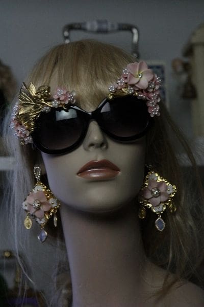 A mannequin wearing sunglasses and earrings with flowers.