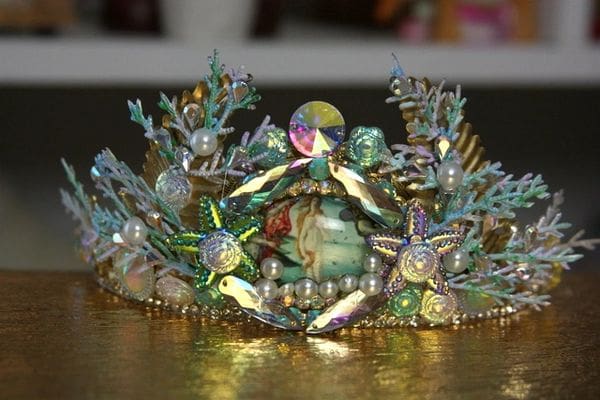 A tiara with green and gold decorations on it.