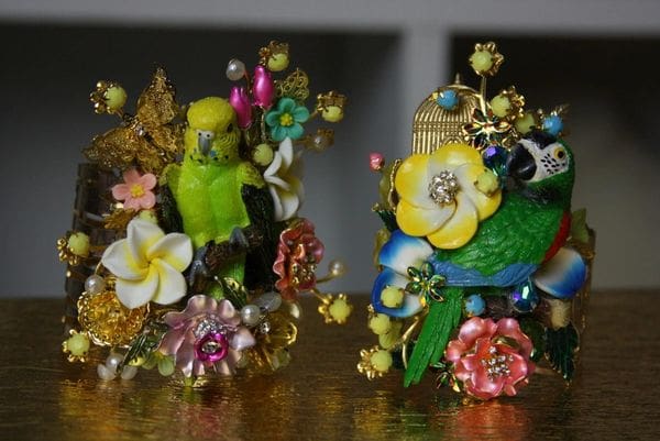 Two figurines of birds and flowers on a table.