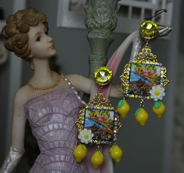 A doll wearing earrings with lemons hanging from them.