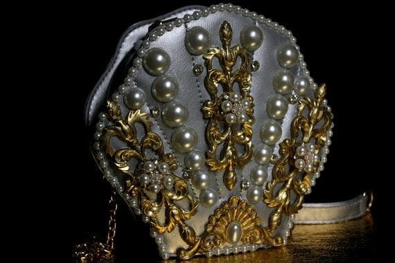 A white purse with gold and pearls on it.