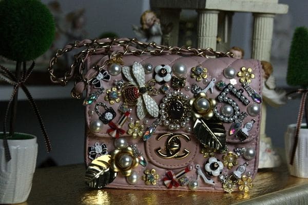A pink purse with many different jewelry on it.