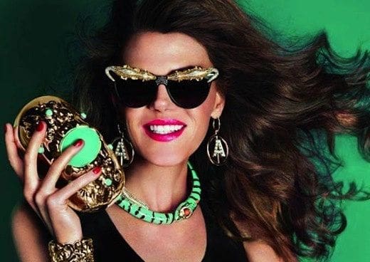 A woman holding a donut in her hand and wearing sunglasses.