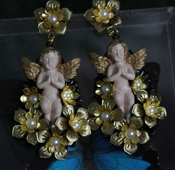 A pair of earrings with gold flowers and angels.